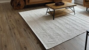 Un salon avec un canapé en cuir marron, une table basse en bois et un tapis à motifs.