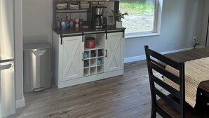 Une cuisine compacte équipée d’un réfrigérateur intégré, d’une machine à café et d’une petite fenêtre donnant sur l’extérieur.