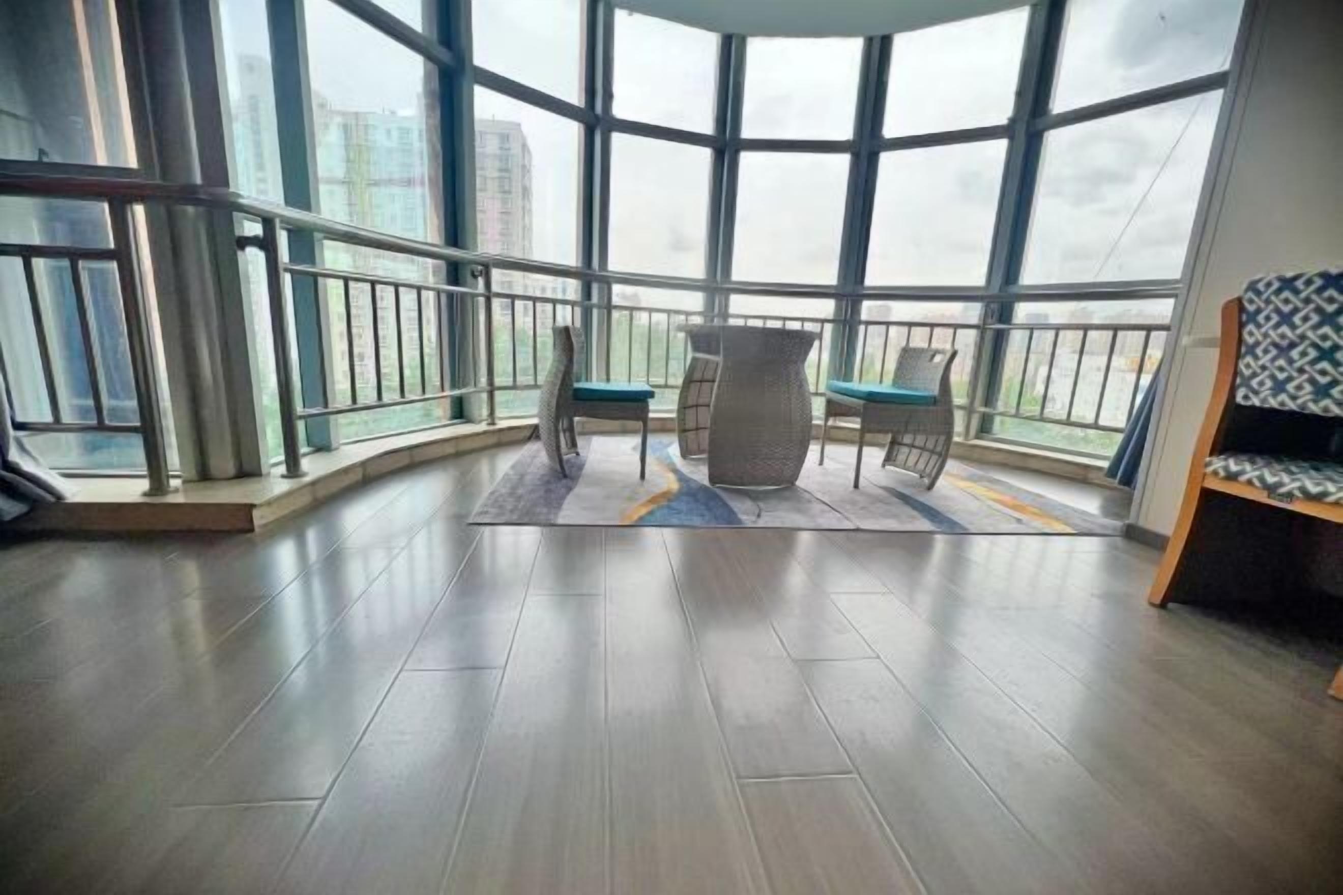 Un balcón con vistas a edificios, una mesa con sillas y un tapete estampado.