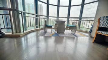 Uma varanda com vista para edifícios, uma mesa com cadeiras e um tapete estampado.