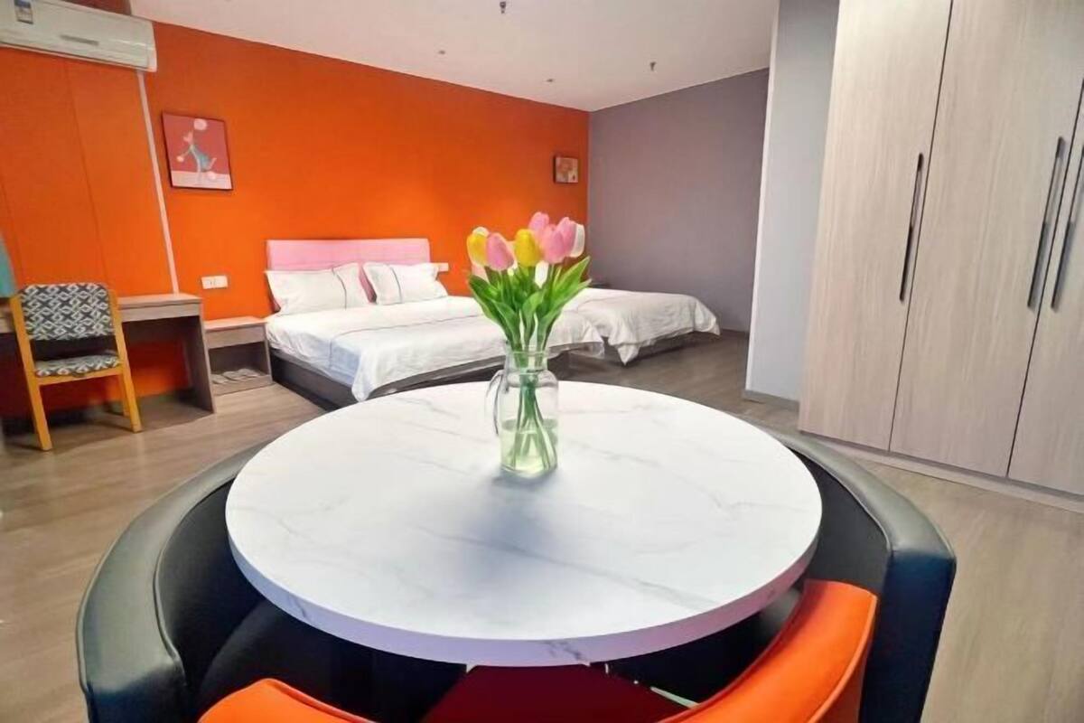 Een hotelkamer met een ronde eettafel, twee bedden, een kledingkast en een stoel.