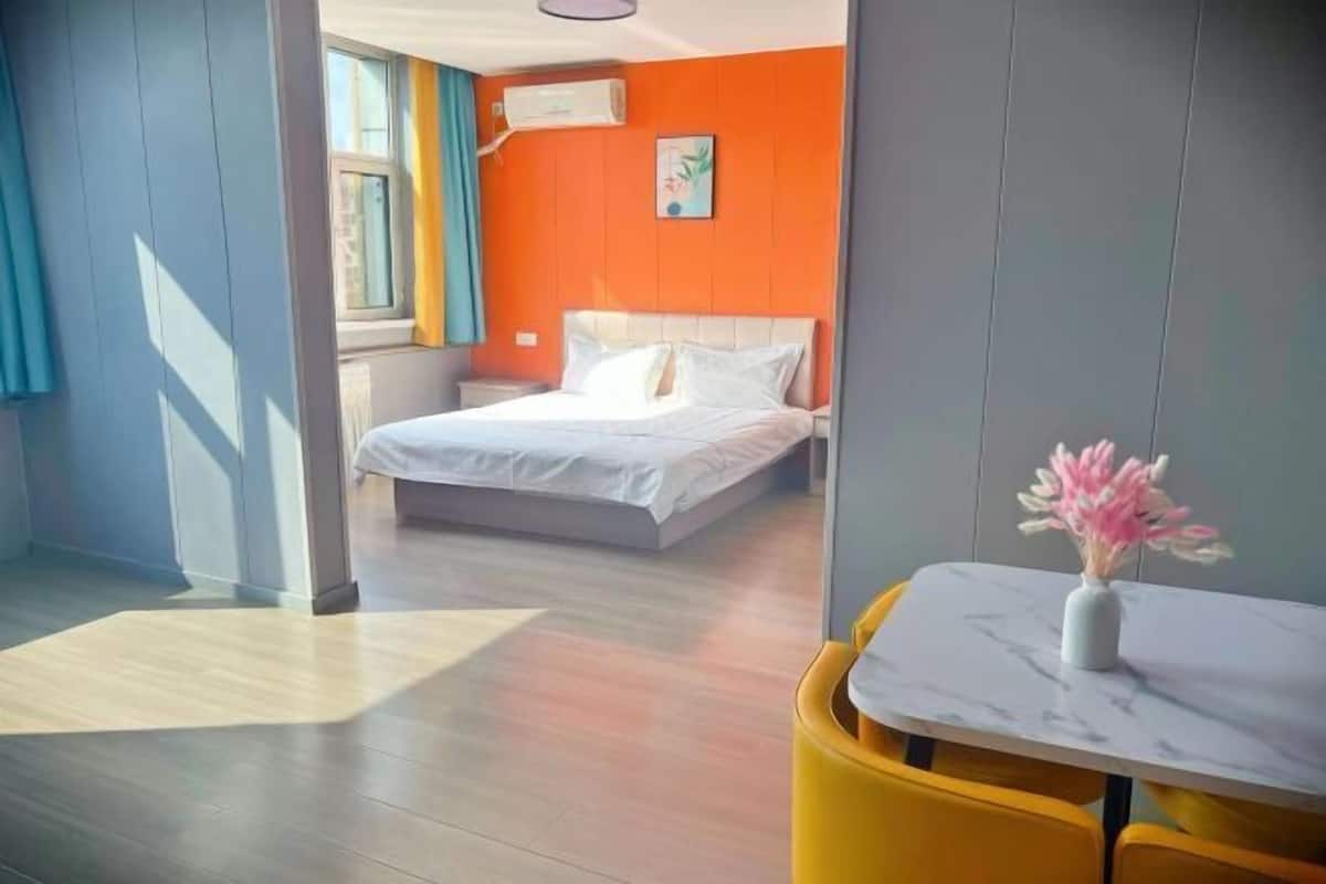 Een hotelkamer met een bed, een tafeltje met een vaas en een raam met gordijnen.