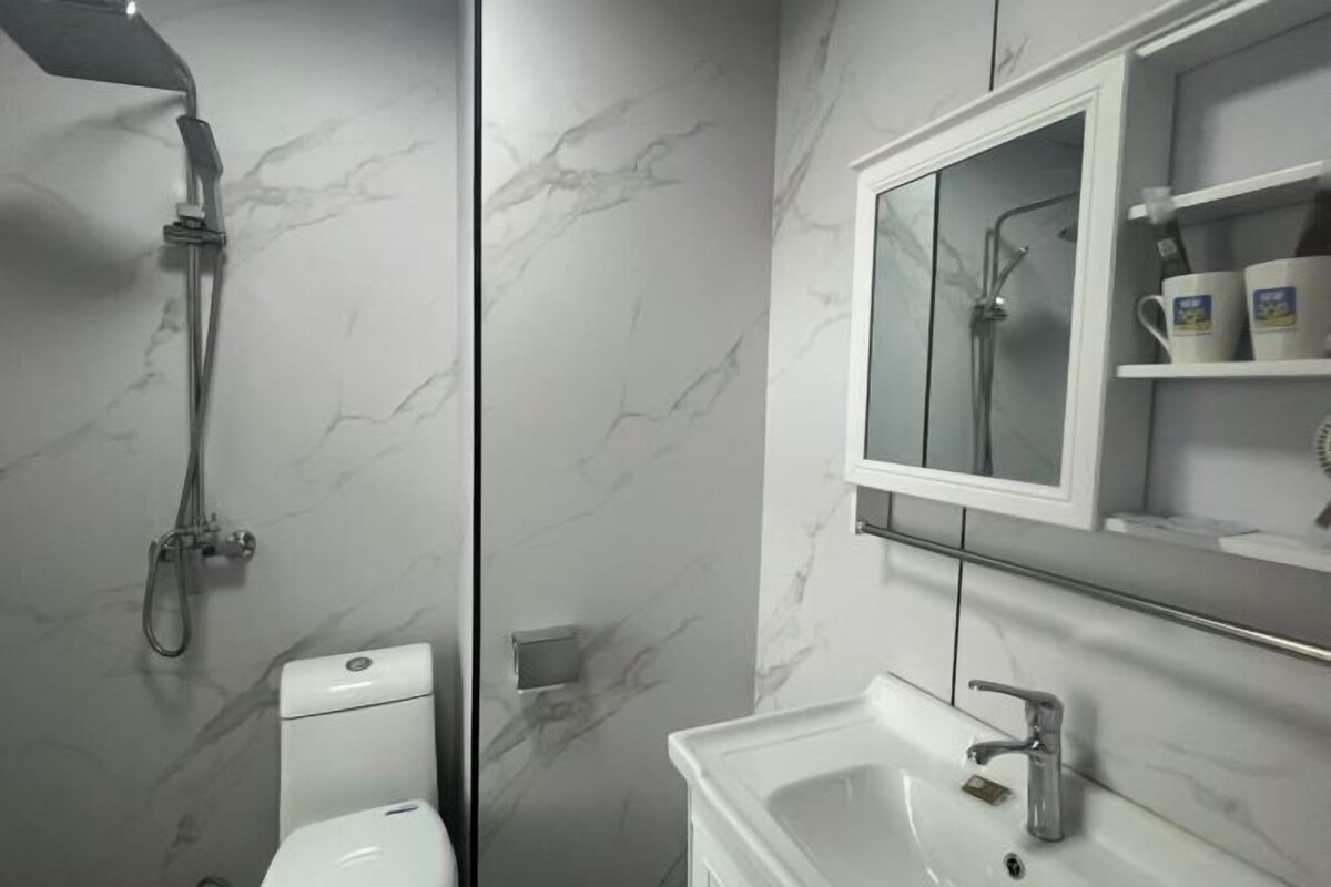 A bathroom with a toilet, shower, and sink.