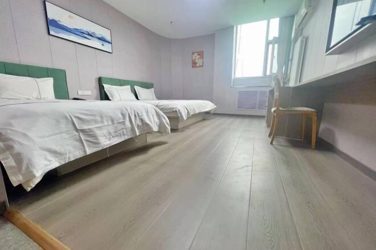Een kamer met twee bedden, een stoel en een raam.