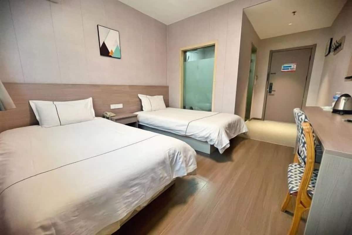 Een hotelkamer met twee bedden, een bureau, een stoel en een deur.