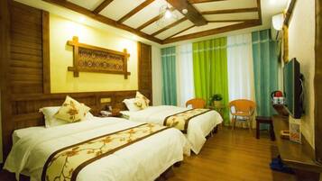 A hotel room with two beds, a desk, a chair, and a television.