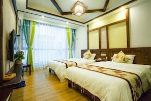 Habitación de hotel con dos camas, televisor, escritorio y ventana con cortinas.