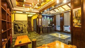 A traditional Japanese-style interior with tatami flooring, wooden furniture, and a reception desk. - Jinhua Inn (Zhangjiajie)