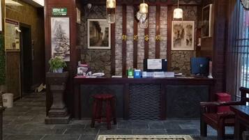 A reception area with a stone wall, wooden paneling, a reception desk, a computer, and a red chair.