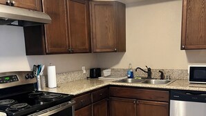 A kitchen with wooden cabinets, a stainless steel stove, a dishwasher, and a microwave.