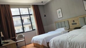 Une chambre d’hôtel avec deux lits, un bureau, une chaise et une grande fenêtre avec des rideaux.