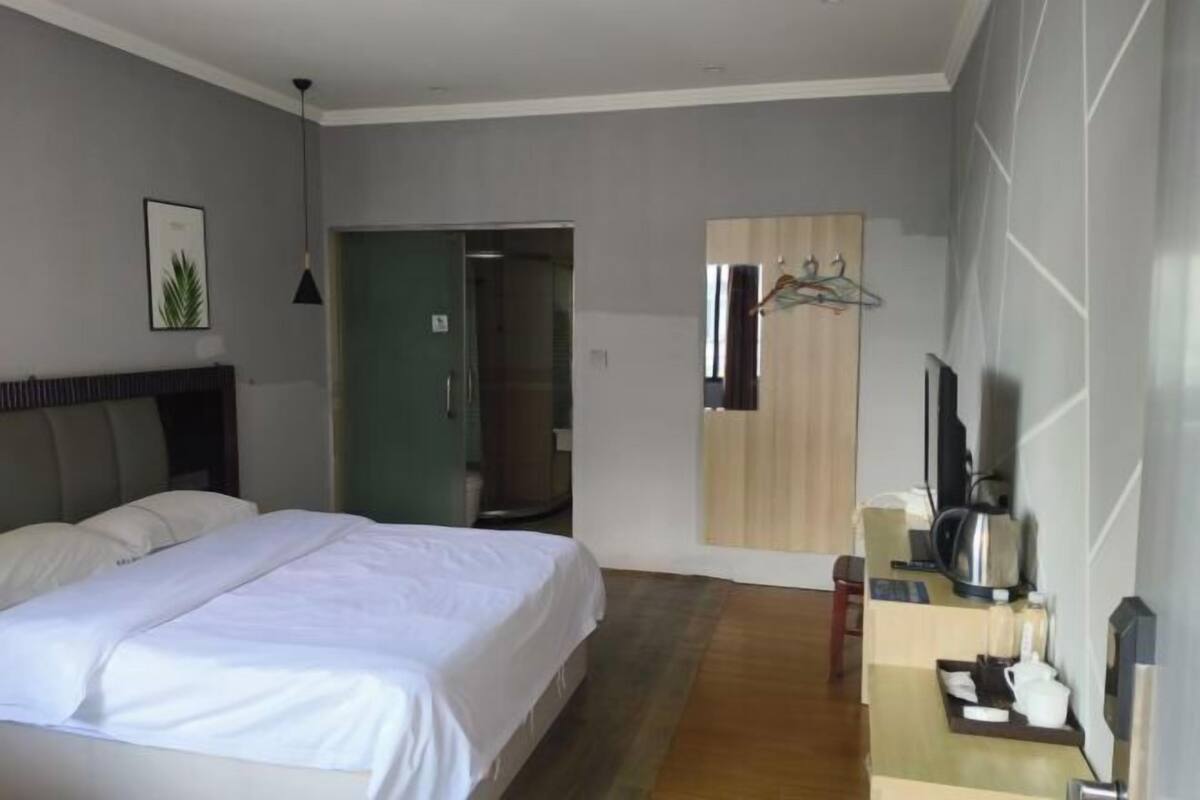 Ein Hotelzimmer mit Bett, Schreibtisch, Kaffeemaschine, Fernseher und Spiegel.