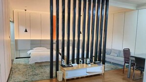 Une chambre d’hôtel moderne avec un lit, une table de chevet et une vue sur l’espace de vie.