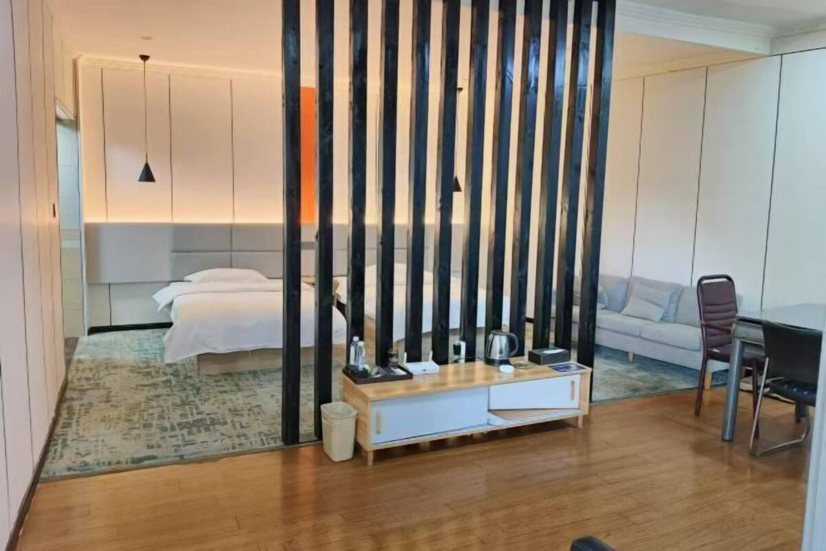 Ein modernes Hotelzimmer mit Bett, Nachttisch und Blick auf den Wohnbereich.
