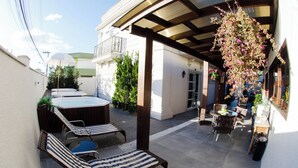 Un patio techado al aire libre con sillones, un jacuzzi y un arreglo floral colgante.
