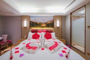 A hotel room with a large bed, a painting on the wall, and a mirror.
