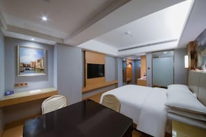 A hotel room with a bed, a desk, a chair, a TV, and a painting on the wall. - Vienna International Hotel (Wanzhou Gaosuntang Pedestrian Street Branch) (Chongqing)