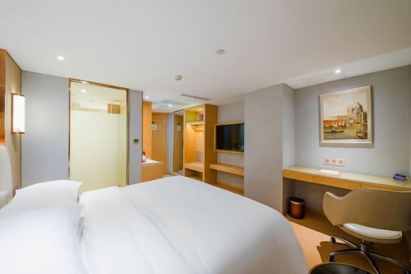 A hotel room with a bed, a desk, a chair, a television, and a painting on the wall. - Vienna International Hotel (Wanzhou Gaosuntang Pedestrian Street Branch) (Chongqing)