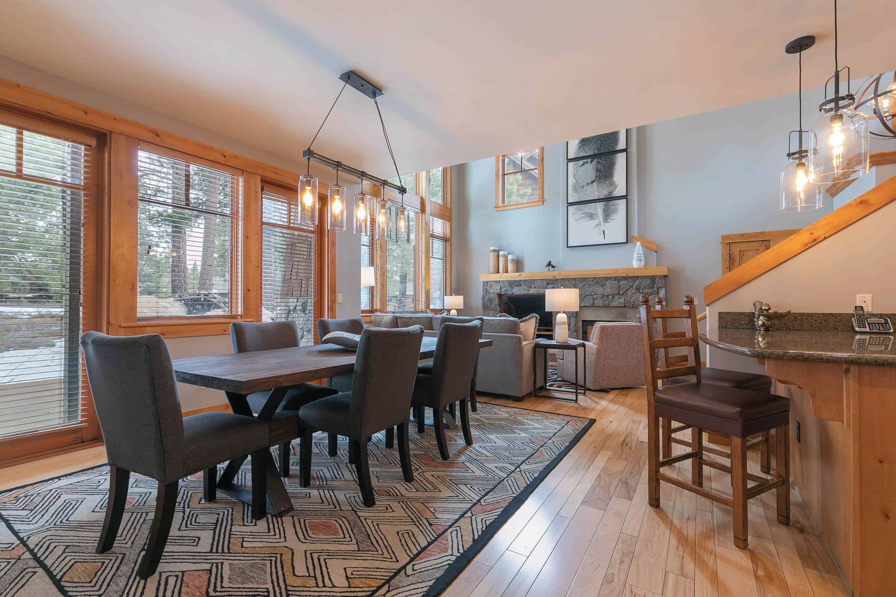 A spacious dining area with a large table and chairs, a fireplace, and a kitchen area with a bar.