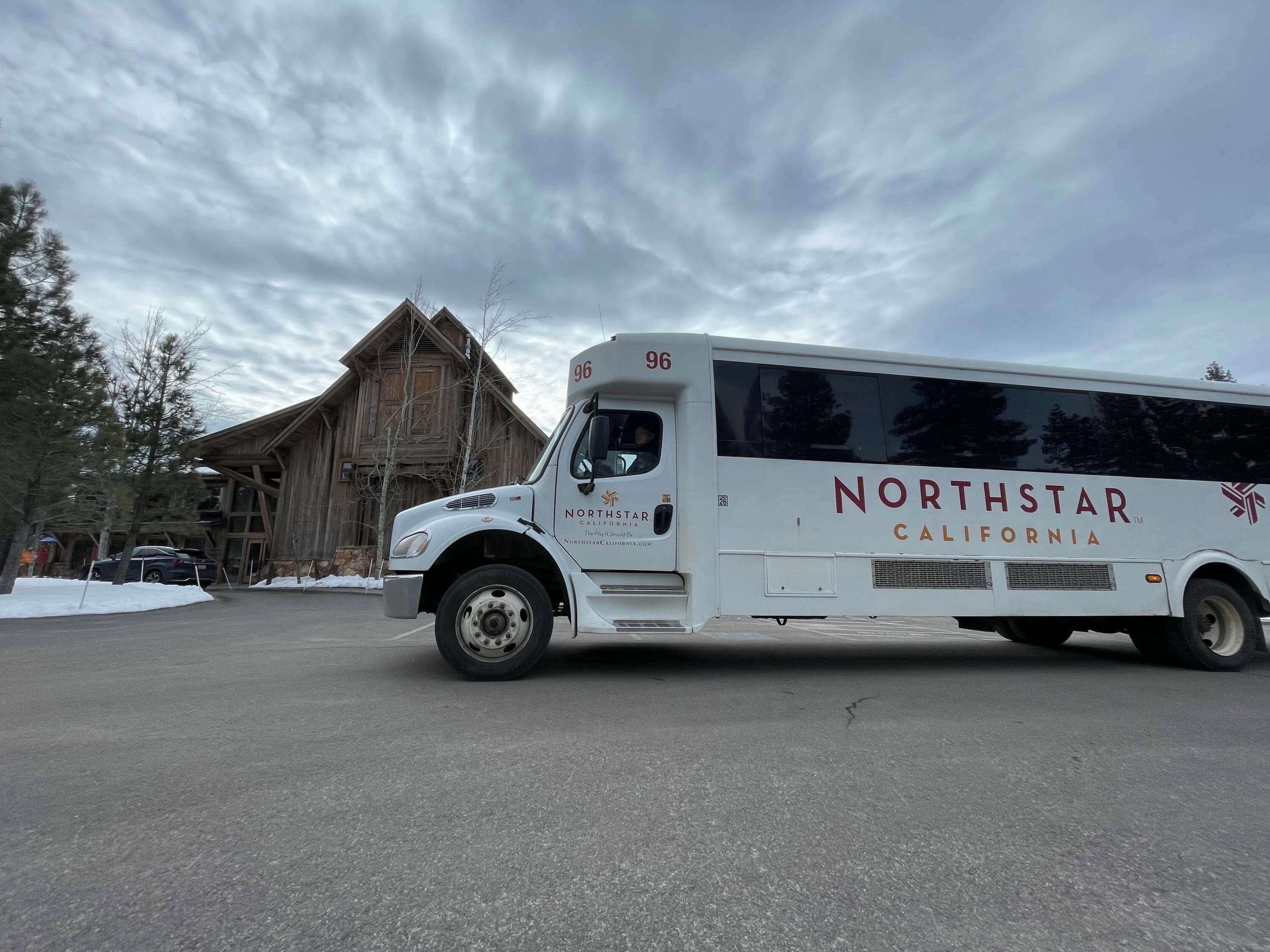 A white NorthStar California bus parked in front of a rustic wooden building.