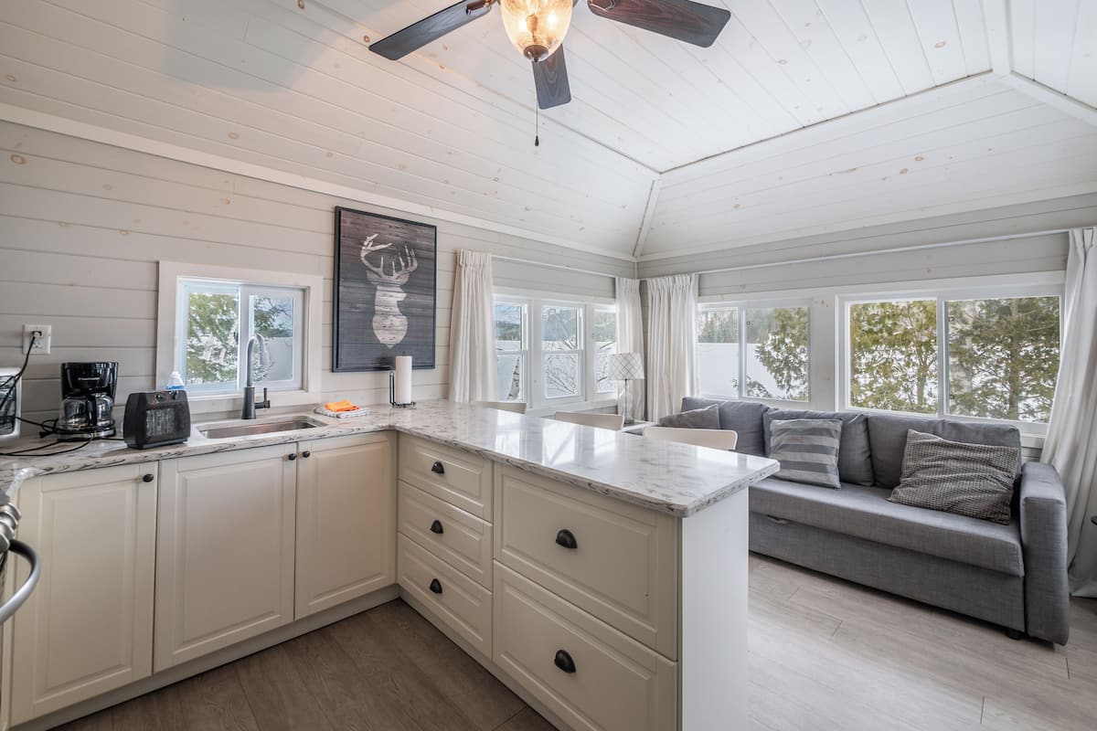 A kitchen with a marble countertop, white cabinets, and a ceiling fan.