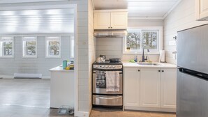Eine moderne Küche mit weißen Schränken, einem Edelstahl-Kühlschrank und einem Gasherd.