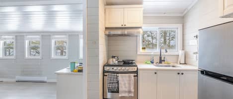 Una cocina moderna con armarios blancos, un refrigerador de acero inoxidable y una estufa a gas.