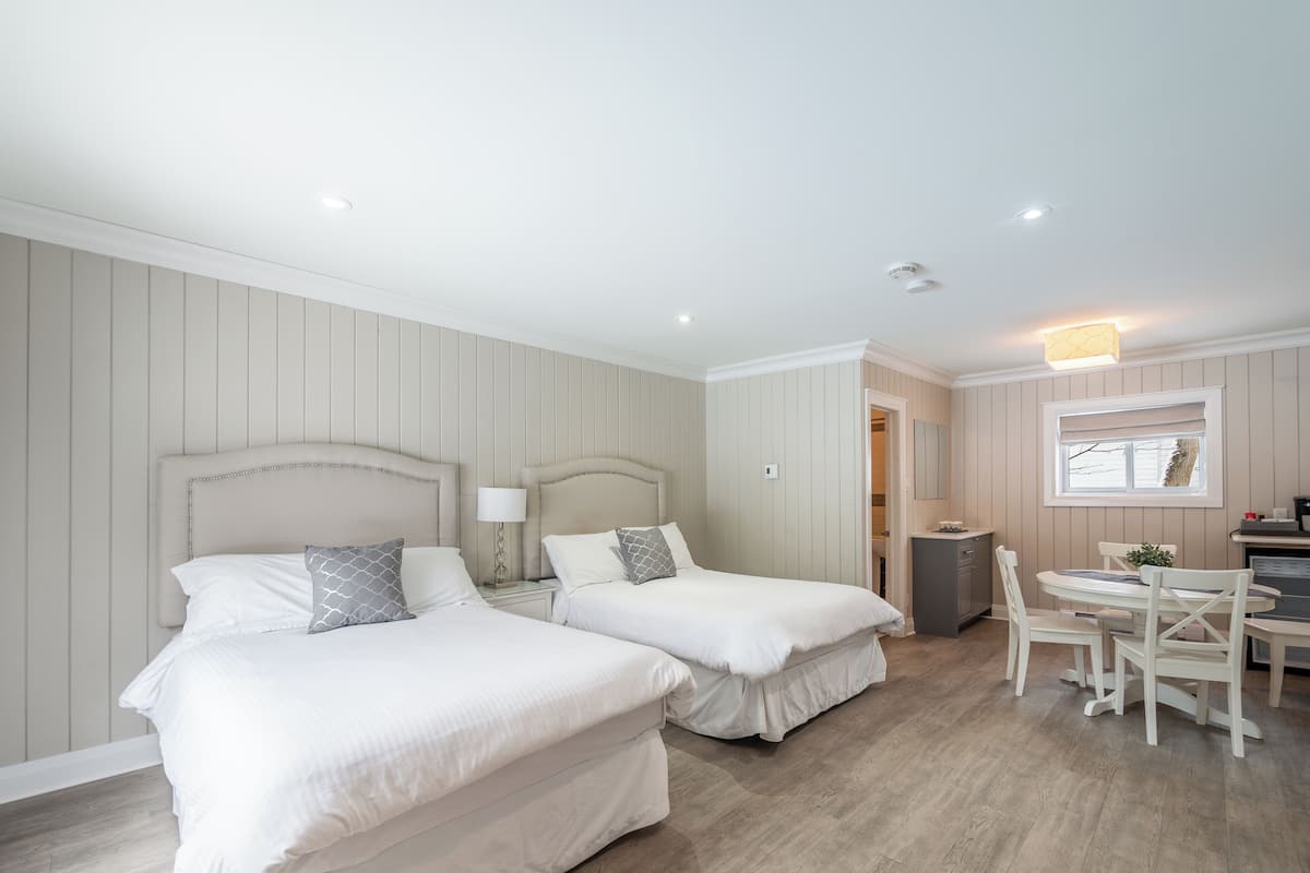 A hotel room with two beds, a dining area, and a small kitchenette.