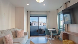 Un salon moderne comprenant un canapé, une table basse, une table à manger avec des chaises, un téléviseur et un balcon avec vue.