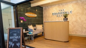La zona de recepción del Hotel Boardwalk, con un mostrador de madera, un cartel de pizarra y una planta en maceta.