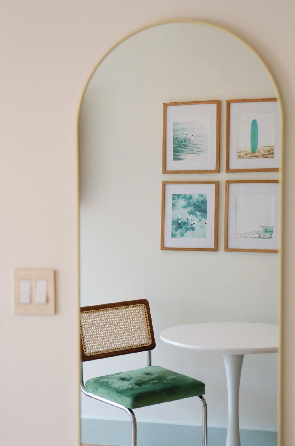 Een kamer met een ronde tafel, een groene fauteuil en vier ingelijste foto's aan de muur.