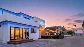 Un bâtiment moderne avec une enseigne indiquant « BOARDSWALK HOTEL » et un patio agrémenté de guirlandes lumineuses.
