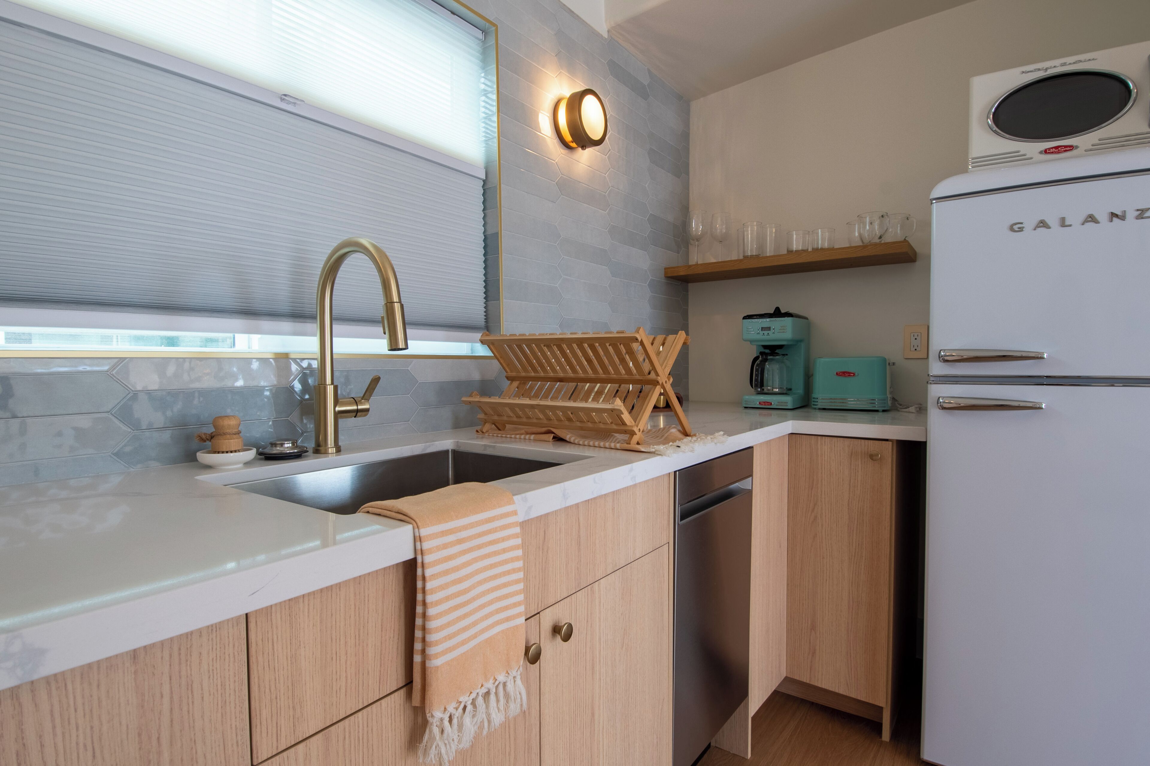 A kitchen with a sink, faucet, wooden cabinets, a white refrigerator, and a coffee maker.