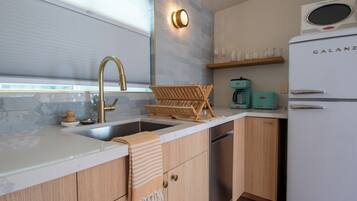 A kitchen with a sink, faucet, wooden cabinets, a white refrigerator, and a coffee maker.