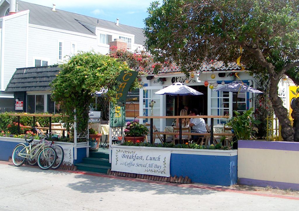 A café with outdoor seating, a sign offering breakfast, lunch, and coffee, and a bicycle parked outside.