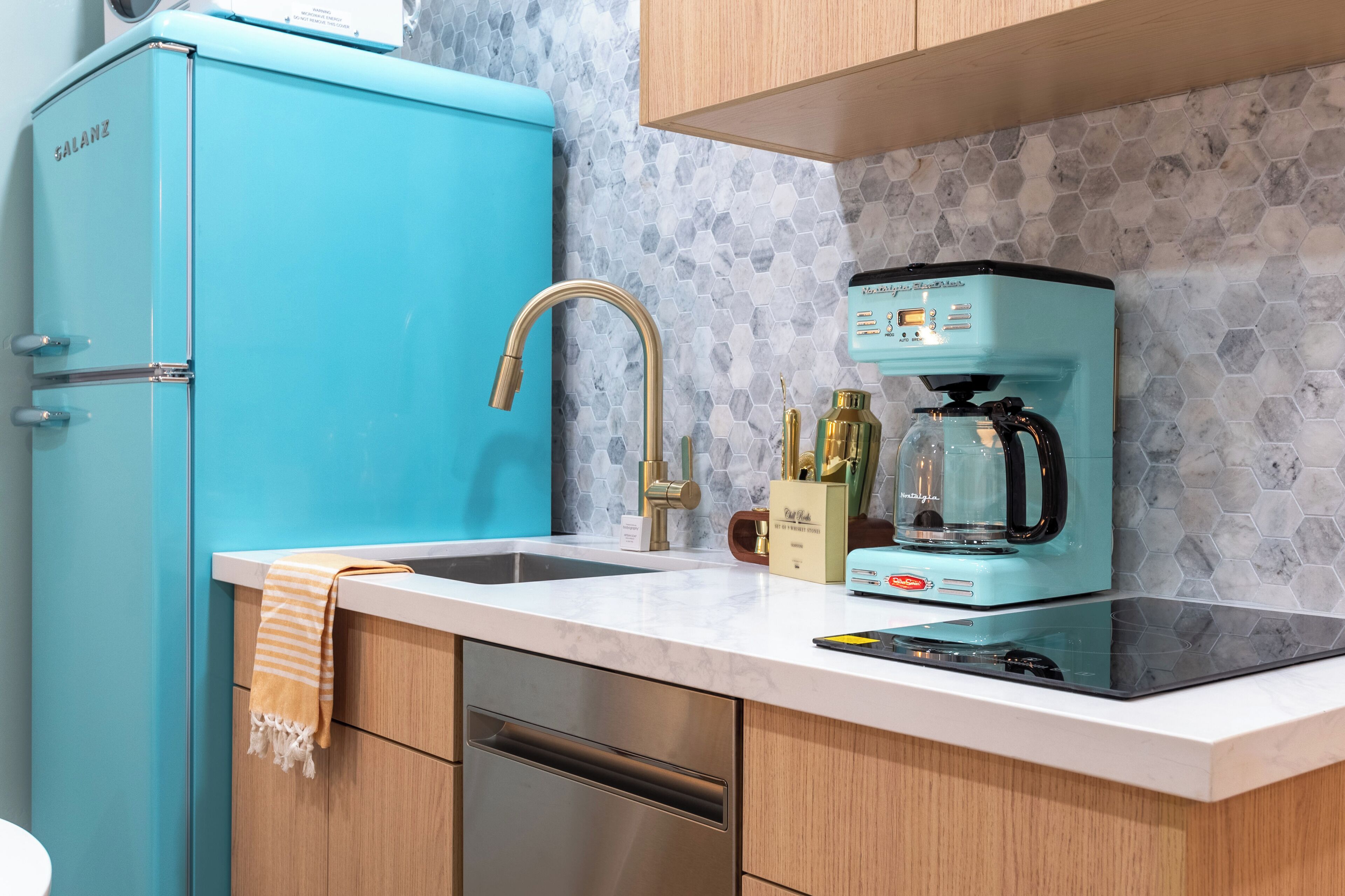 A kitchen with a teal refrigerator, a coffee maker, and a sink.