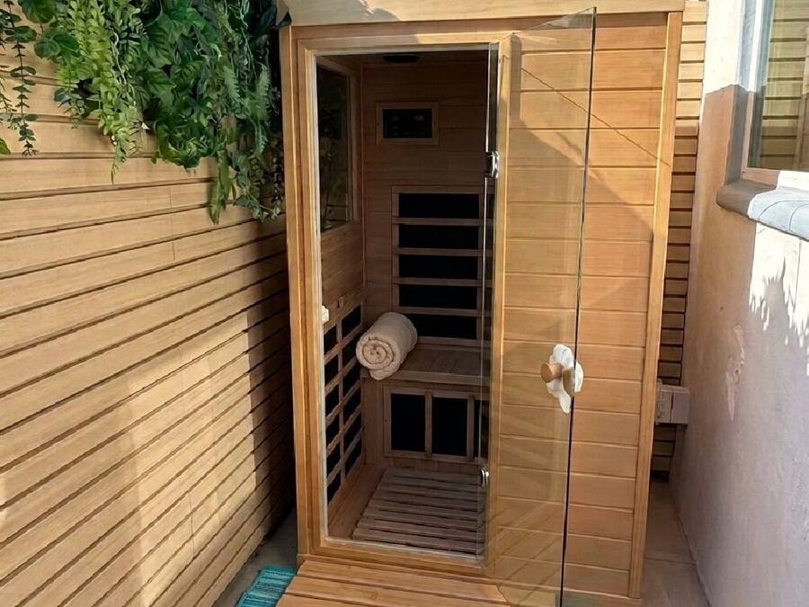 A wooden sauna with a glass door, a towel, and a wooden bench.