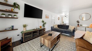 A modern living room with a flat-screen TV, wooden shelves, a sofa, and a coffee table.