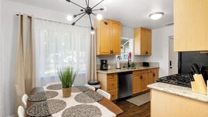 A modern kitchen with wooden cabinets, a gas stove, and a coffee maker.