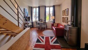 En moderne stue med trappe, en rød sofa, trægulv og et tæppe med Union Jack.
