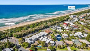 An aerial view of a coastal residential area with a beach access point, a surf club, and a property named 'belle property escapes'. - Pet Friendly Marcoola Surfside Escape (Marcoola)
