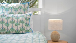 A bed with patterned pillows and a lamp on a bedside table. - Pet Friendly Marcoola Surfside Escape (Marcoola)