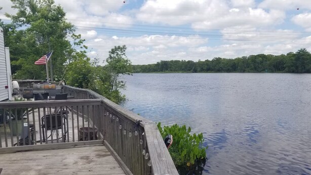 Un muelle de madera se extiende sobre un lago tranquilo, con una bandera a la izquierda.