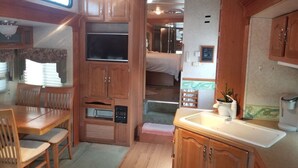 Interior compacto de autocaravana con zona de comedor, kitchenette y cama.