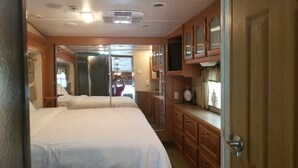 Un dormitorio con dos camas, armarios de madera, un televisor y un espejo.