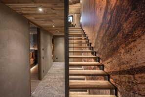 Staircase leads to an upper level, flanked by paneling and a textured wall.