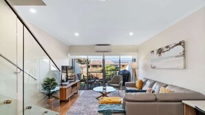Ein modernes Wohnzimmer mit einer Glastreppe, einem Sofa, einem Couchtisch und Blick ins Freie.