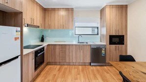 Eine moderne Küche mit Holzausstattung, einem Geschirrspüler, einer Mikrowelle und einem Essbereich mit Tisch und Stühlen.