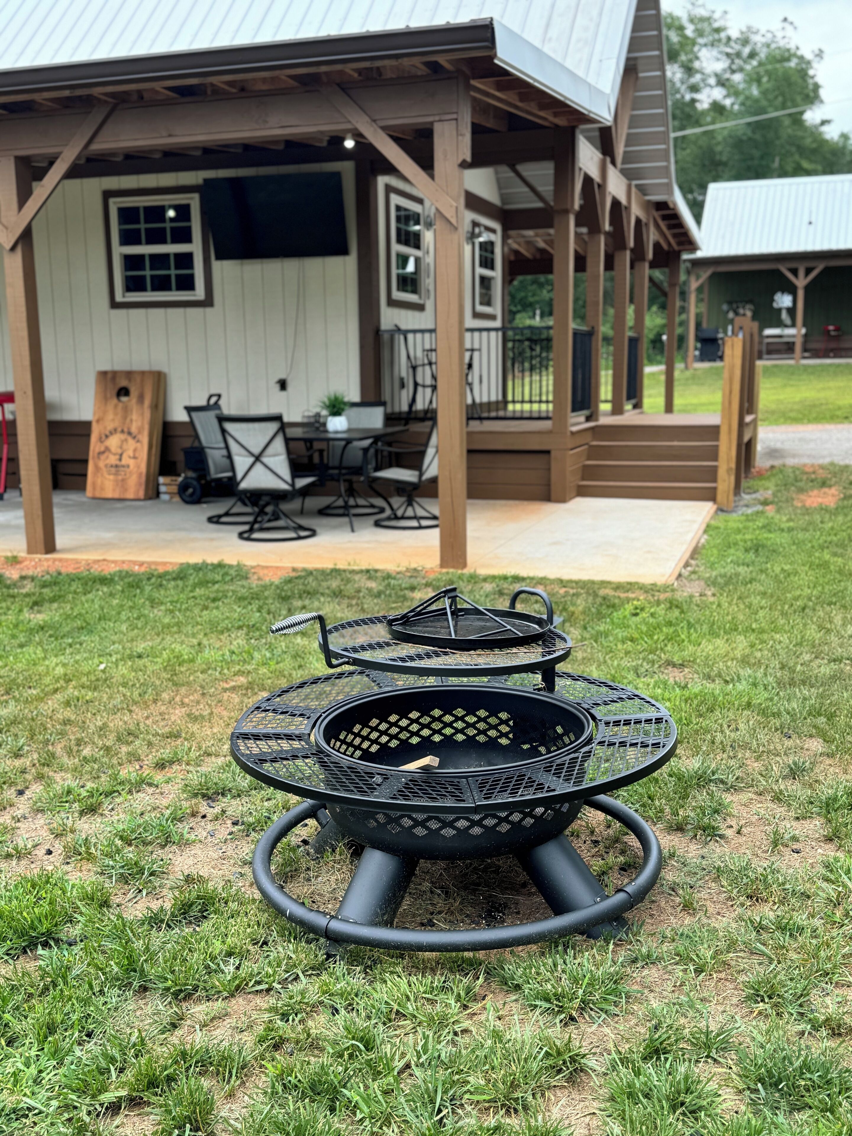 A covered outdoor seating area with a grill and chairs.