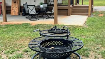 A covered outdoor seating area with a grill and chairs.